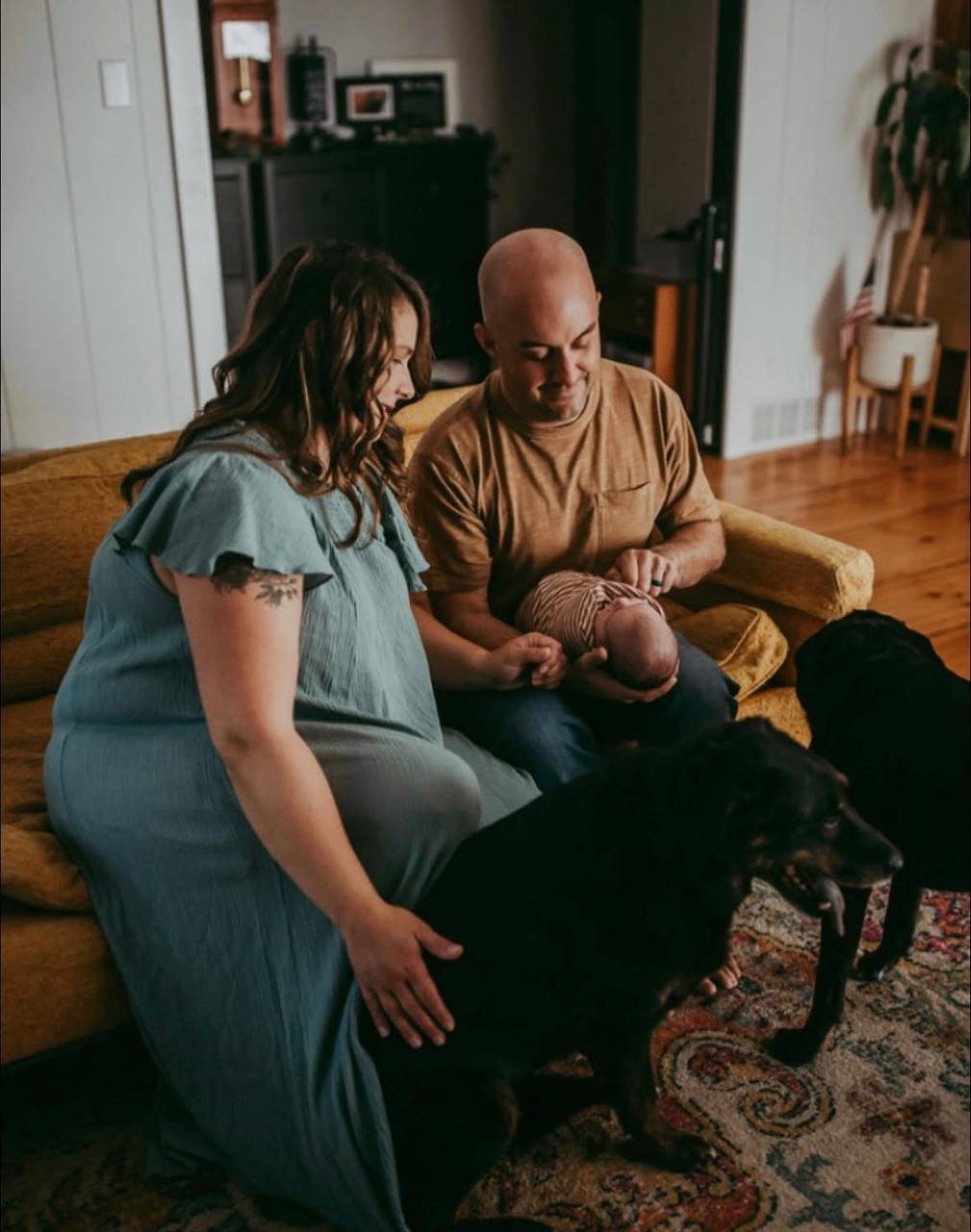 Kourtney supporting a family with their newborn on a cozy couch with the family dog