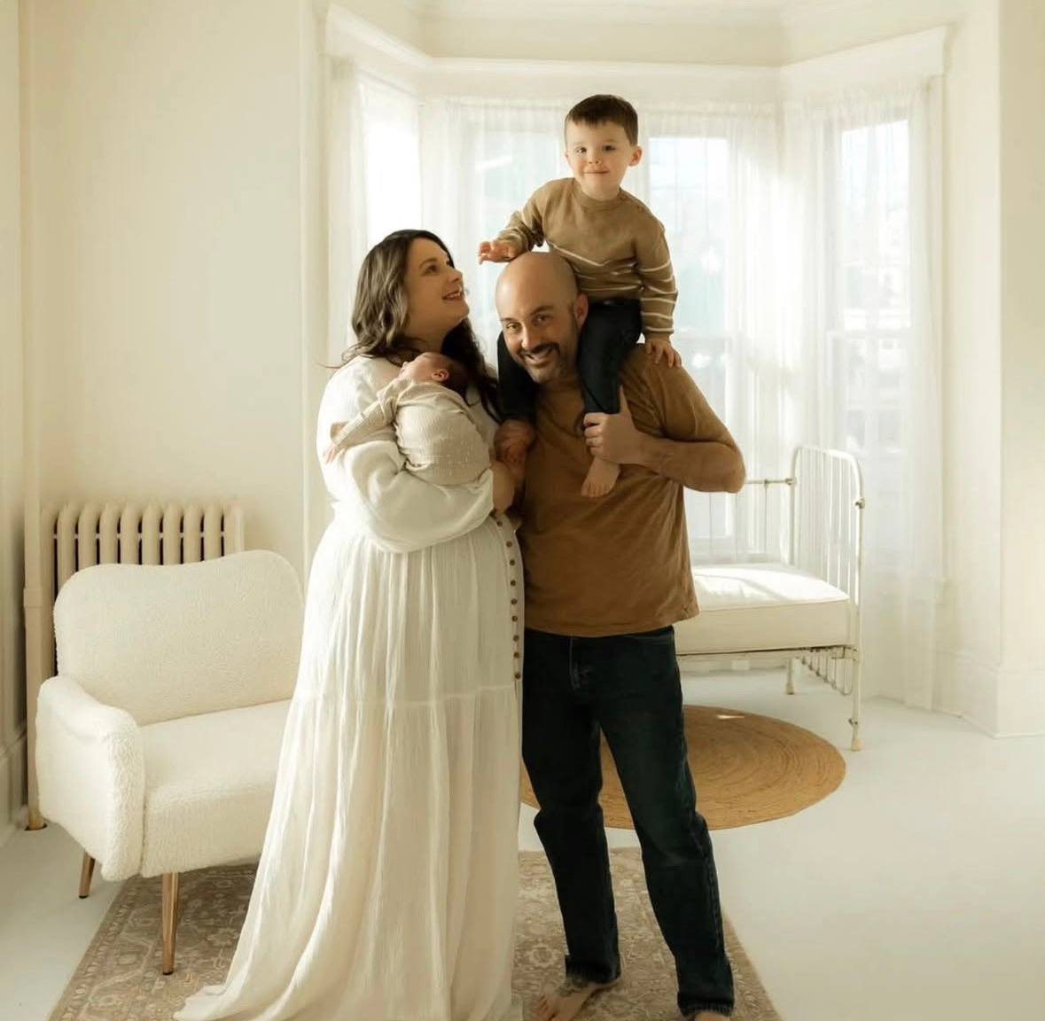 Joyful family of four in a bright studio, celebrating their new baby